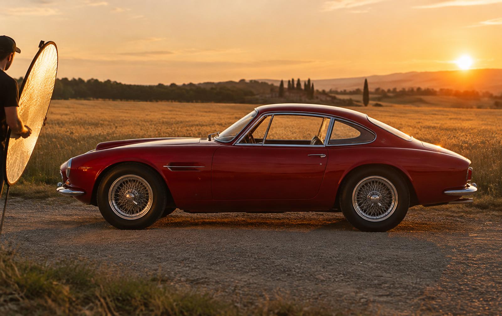 Coupé sportif rouge des années 60 de profil, en lumière dorée, lors d'une séance photo